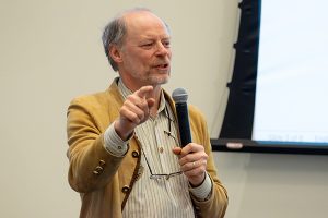 Dr. Titus Schleyer holding microphone giving a presentation at the 2025 AI Conference.